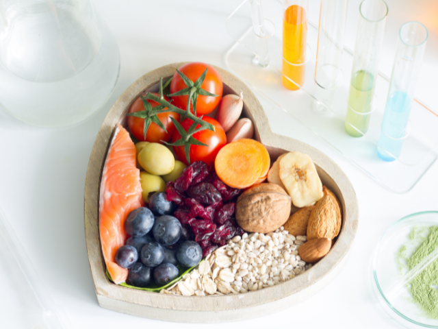 A heart-shaped bowl filled with nutrient-rich foods like salmon, tomatoes, nuts, and berries.