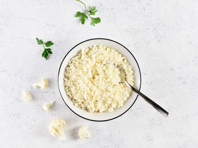 A bowl of fresh cauliflower rice, garnished with parsley.