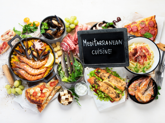 A diverse spread of Mediterranean dishes, including seafood, salads, and pasta, arranged beautifully with a signboard displaying "Mediterranean Cuisine.