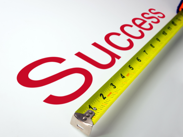 A measuring tape placed on the word "Success" on a white background.