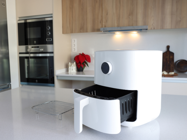 White air fryer with an open drawer on a kitchen counter.