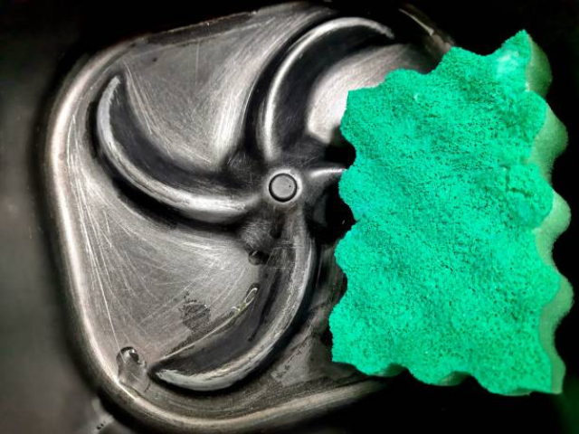 A green sponge placed inside the base of an air fryer, showcasing the cleaning process of the appliance.