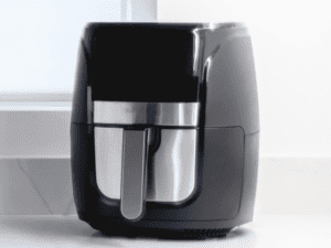 Black air fryer placed on a white countertop.