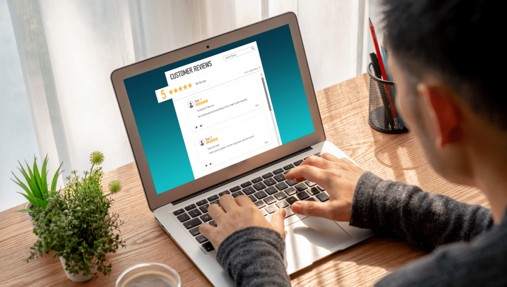 A person typing a customer review on a laptop, showcasing a 5-star review system on the screen.
