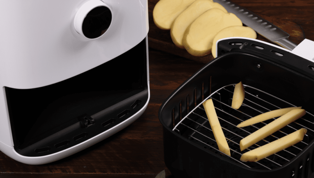 An air fryer basket with potato slices ready for cooking.