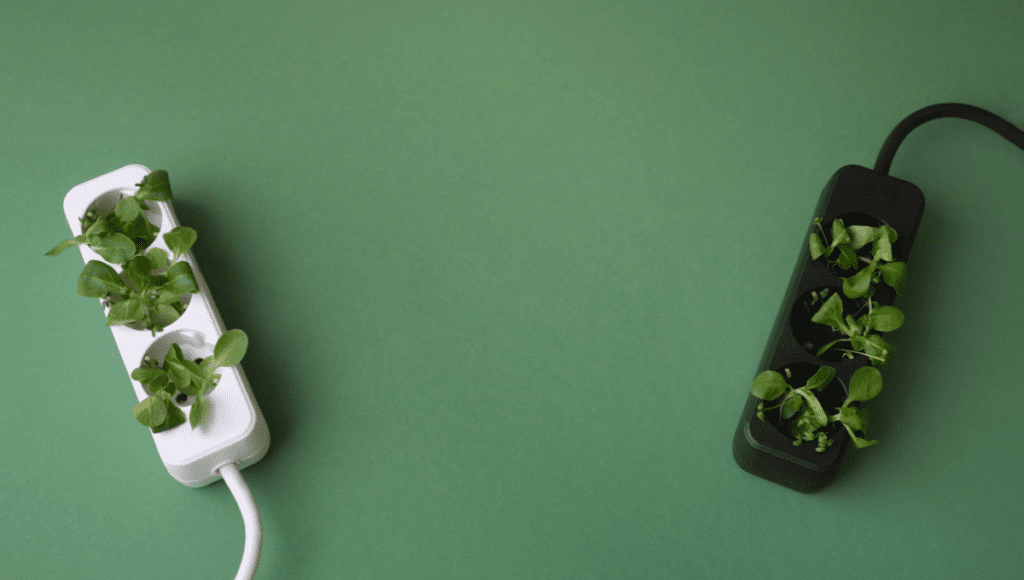 White and black power strips with plants growing from their sockets, set against a green background, highlighting the concept of green energy.