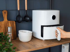 A person opening a white air fryer in a stylish kitchen setup.