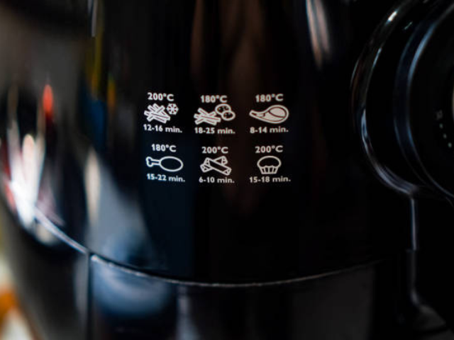 Close-up of an air fryer with cooking instructions displayed on the device.