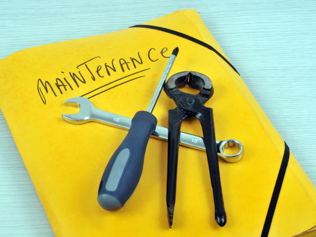 Tools and wrench placed on a yellow folder labeled "Maintenance.