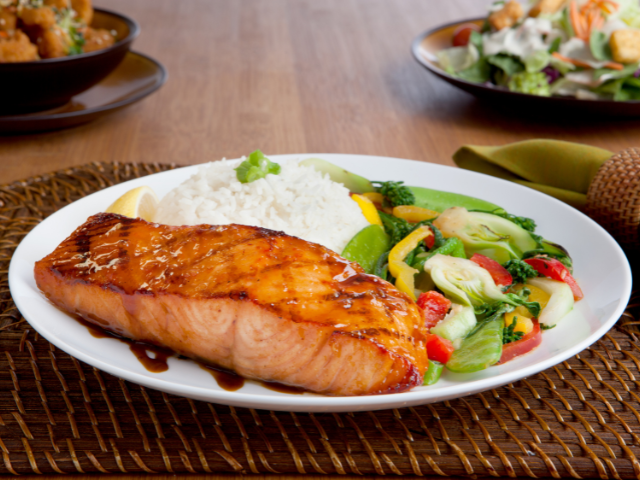 Grilled salmon with rice and stir-fried vegetables on a plate.