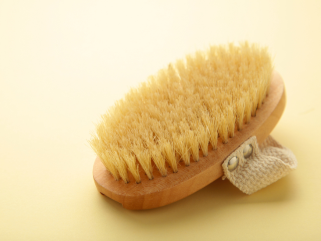 A dry brush with natural bristles on a light yellow background.