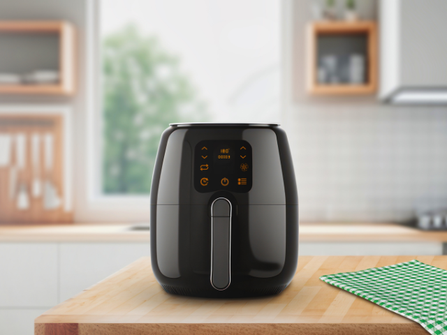 A modern black air fryer with an illuminated control panel on a kitchen counter.