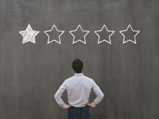 A person standing in front of a chalkboard with a single star marked out of five.