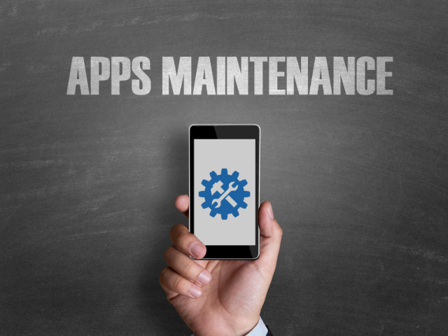 A smartphone displaying an app maintenance symbol held against a chalkboard with "APPS MAINTENANCE" written on it.