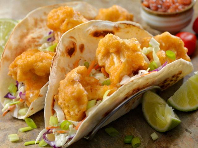 Crispy chicken tacos with lime wedges and salsa on the side.