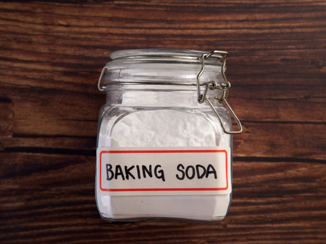 A labeled jar of baking soda placed on a wooden table.