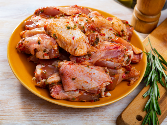 A plate of marinated chicken wings, seasoned and ready for grilling.