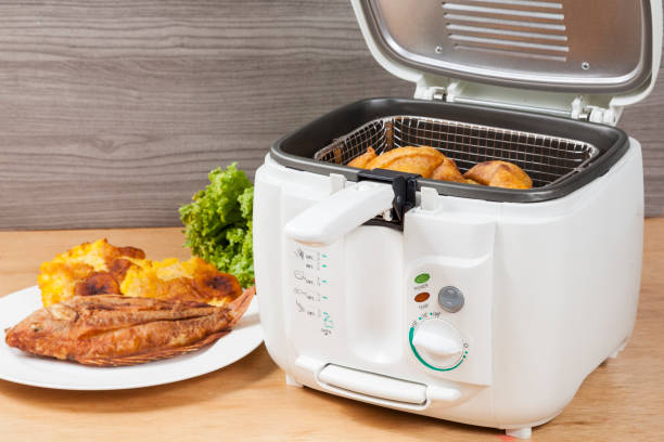 Deep fryer with fried chicken and crispy potatoes on a plate.