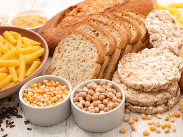 Various types of bread, pasta, and grains displayed on a wooden surface.